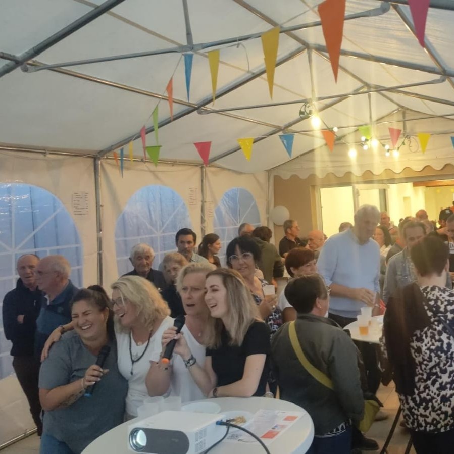 Un public festif en train de chanter dans une soirée karaoké organisée par un comité des fêtes.